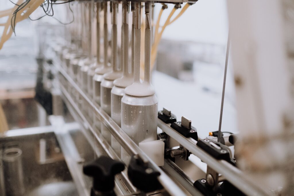 Automated bottle-filling production line dispensing white liquid formula into bottles, representing the industrial-scale manufacturing process behind Malaysia's OEM laundry and dishwash detergent factories featured in this 2026 Malaysia OEM guide.
